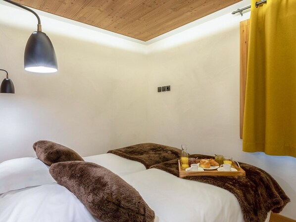Un dormitorio con cama, lámpara de noche, bandeja con alimentos para el desayuno y una cortina amarilla.