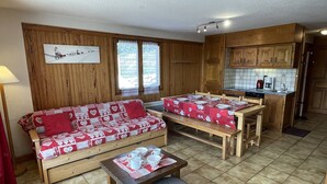 Ett mysigt rum med en soffa och ett matbord, träskåp och ett klinkergolv.