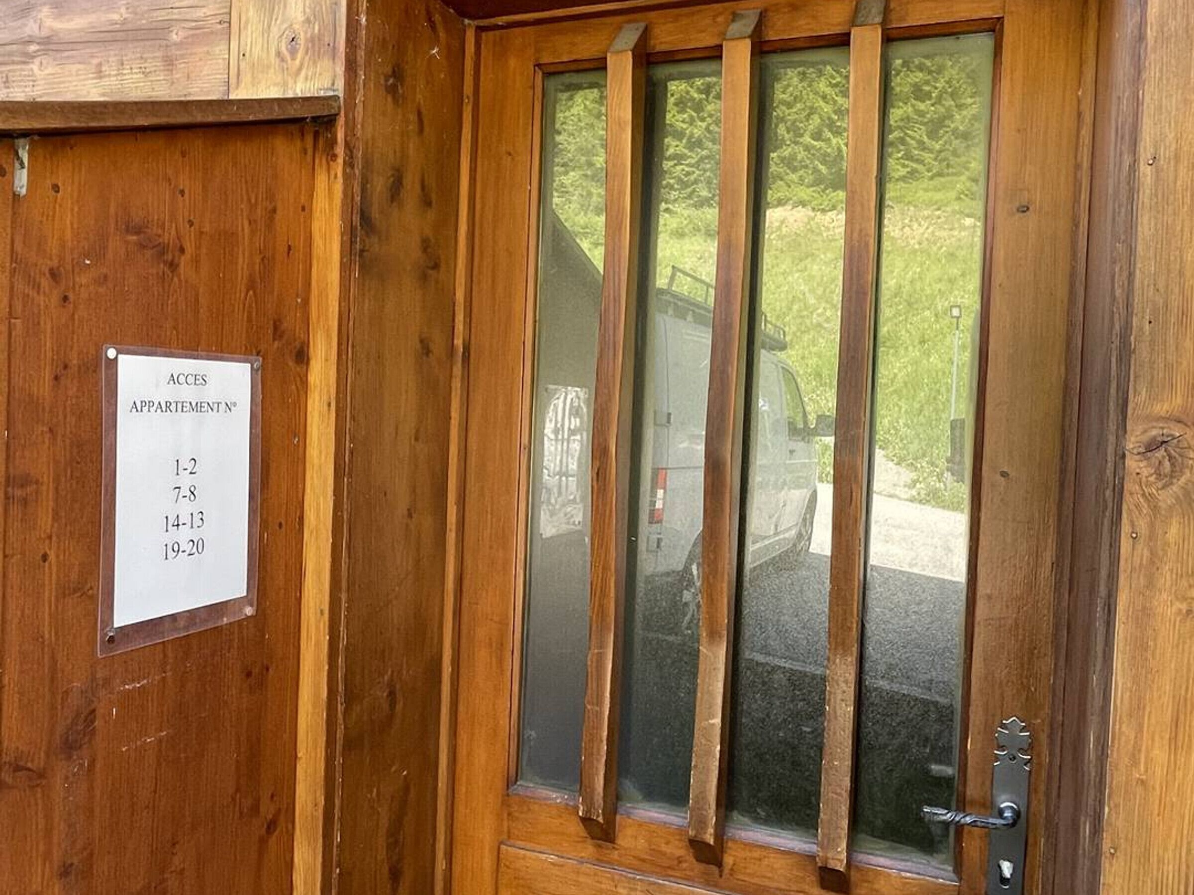 Eine Holztür mit einem Schild, das die Apartmentnummern 1-2, 7-8, 14-13 und 19-20 anzeigt.