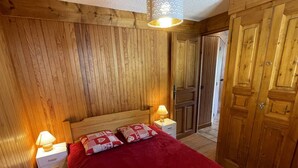 Ett rum med träpanel på väggarna, en säng, två sänglampor och ett rött överkast.