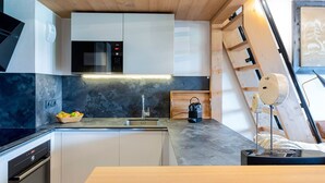 A modern kitchen with a wooden ceiling, built-in appliances, and a marble countertop.