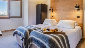 A modern bedroom with two beds, a wooden headboard, a wardrobe, and a breakfast tray on the bed. - 4* Apartment with SPA - Les Saisies, 4 ppl, private parking (Les Saisies)