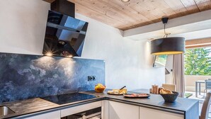 A modern kitchen with a built-in stove, oven, and a large island with a bowl of fruit and cheese. - 4* Apartment with SPA - Les Saisies, 4 ppl, private parking (Les Saisies)