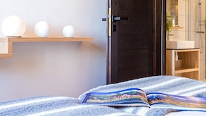 A modern bedroom with a bed, a book, and a door leading to a bathroom.