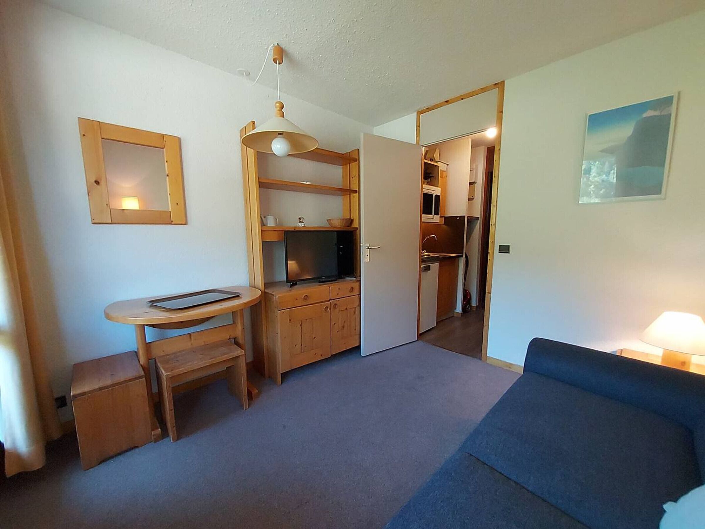 Un espacio habitable compacto con kitchenette, comedor y zona de estar.