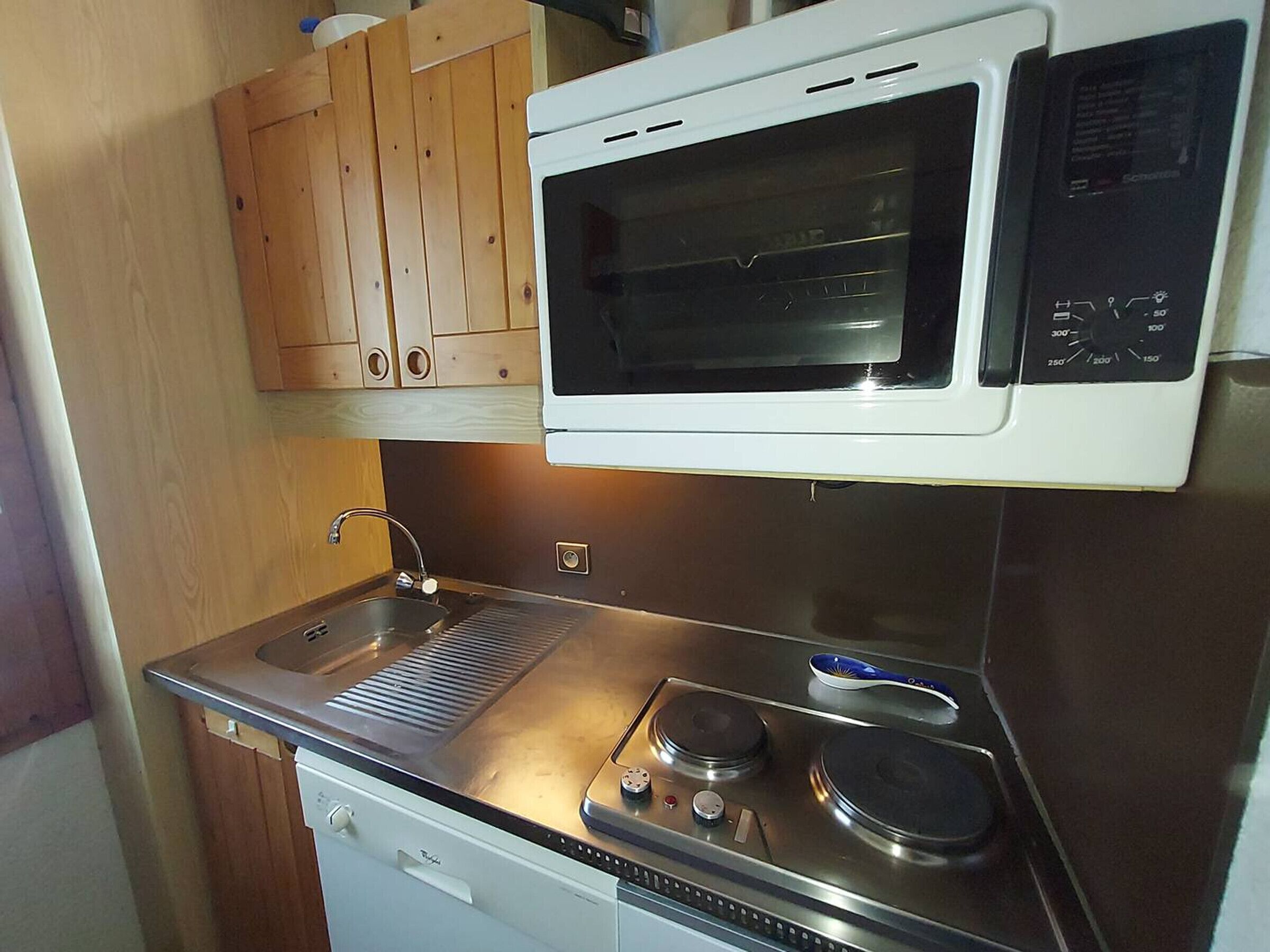 A compact kitchen with a built-in microwave, a stovetop, and a sink.