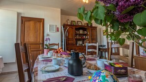 A dining area with a table set for a meal, surrounded by wooden chairs. - Guest rooms with garden near Loire castles (Châtillon-sur-Indre)