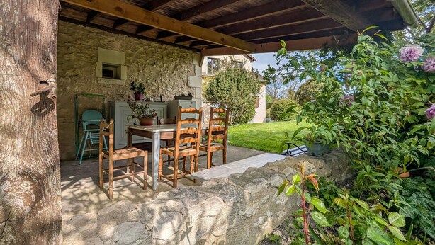 A rustic stone building with a wooden table and chairs under a wooden roof. - Guest rooms with garden near Loire castles (Châtillon-sur-Indre)