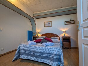 A neatly made bed with patterned bedding, two bedside lamps, a framed picture on the wall, and a blue door. - Tranquil B&B near Castles and Beauval Zoo (Châtillon-sur-Indre)