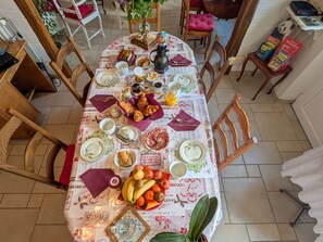 A dining table set with various dishes, fruits, and a vase. - Tranquil B&B near Castles and Beauval Zoo (Châtillon-sur-Indre)