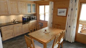 A wooden kitchen with a dining table and chairs, a microwave, and a coffee maker.