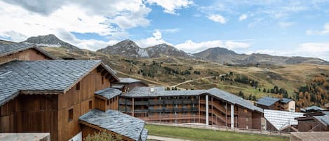 Un edificio de madera con techo inclinado, rodeado de montañas y cielo despejado.