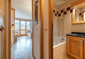 A bathroom with a bathtub, shower, and wooden cabinets. - Smartstay Themis - Belle Plagne (Belle-Plagne)