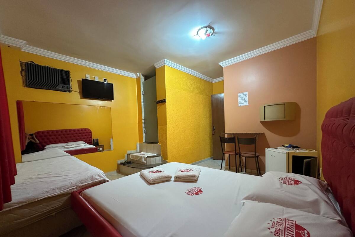 A hotel room with two beds, a TV, a desk, and a chair.