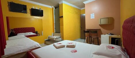 A hotel room with two beds, a TV, a desk, and a chair.
