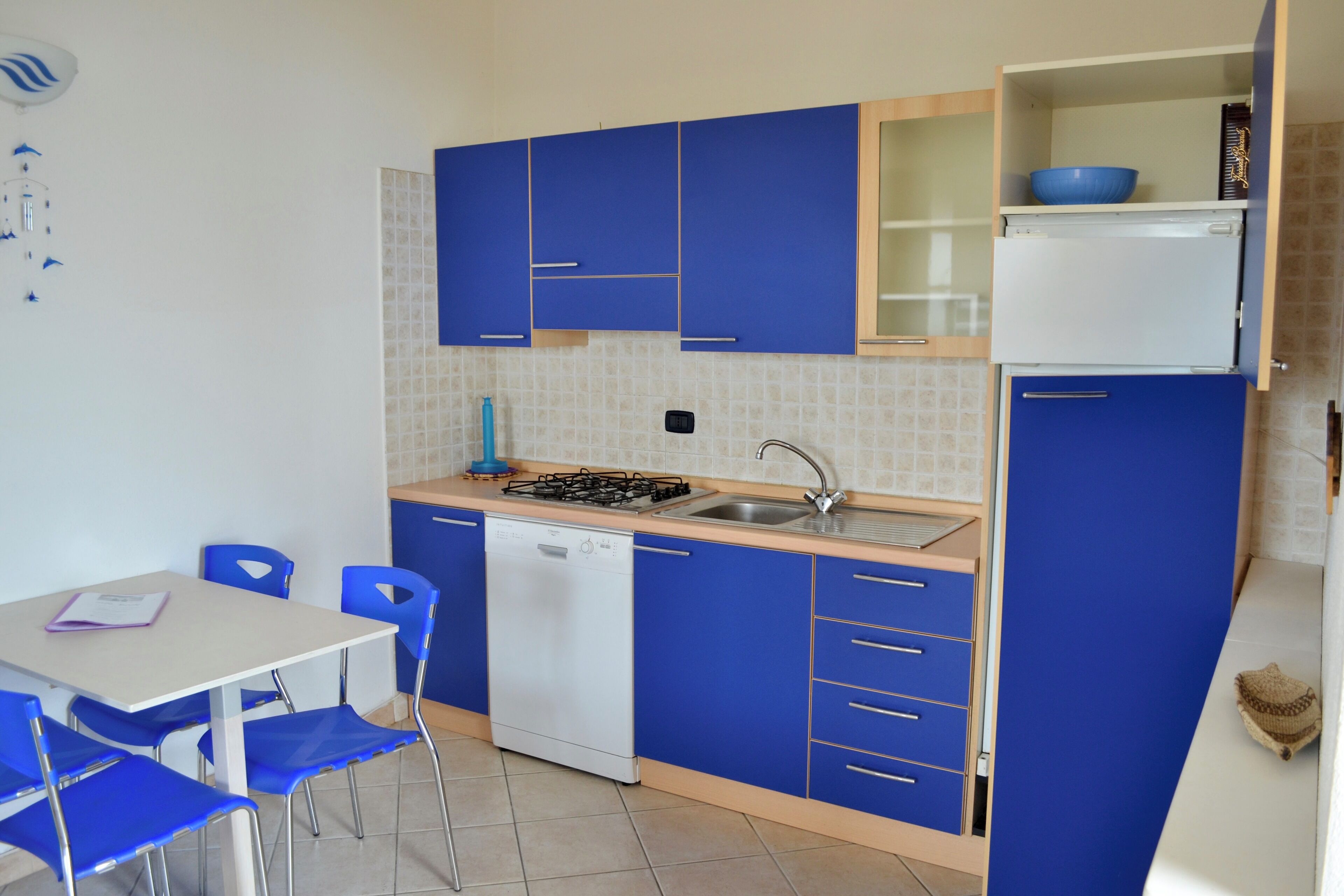 A compact kitchen with blue cabinets, a white dishwasher, and a sink.
