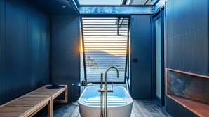 A modern bathroom with a skylight, a freestanding bathtub, and a wooden bench. - Mountain Top Bilpin, Studio 2 (Bilpin)