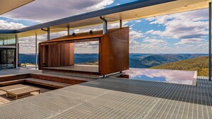 A modern outdoor lounge area with a wooden structure, a pool, and a view of the mountains. - Mountain Top Bilpin, Studio 2 (Bilpin)