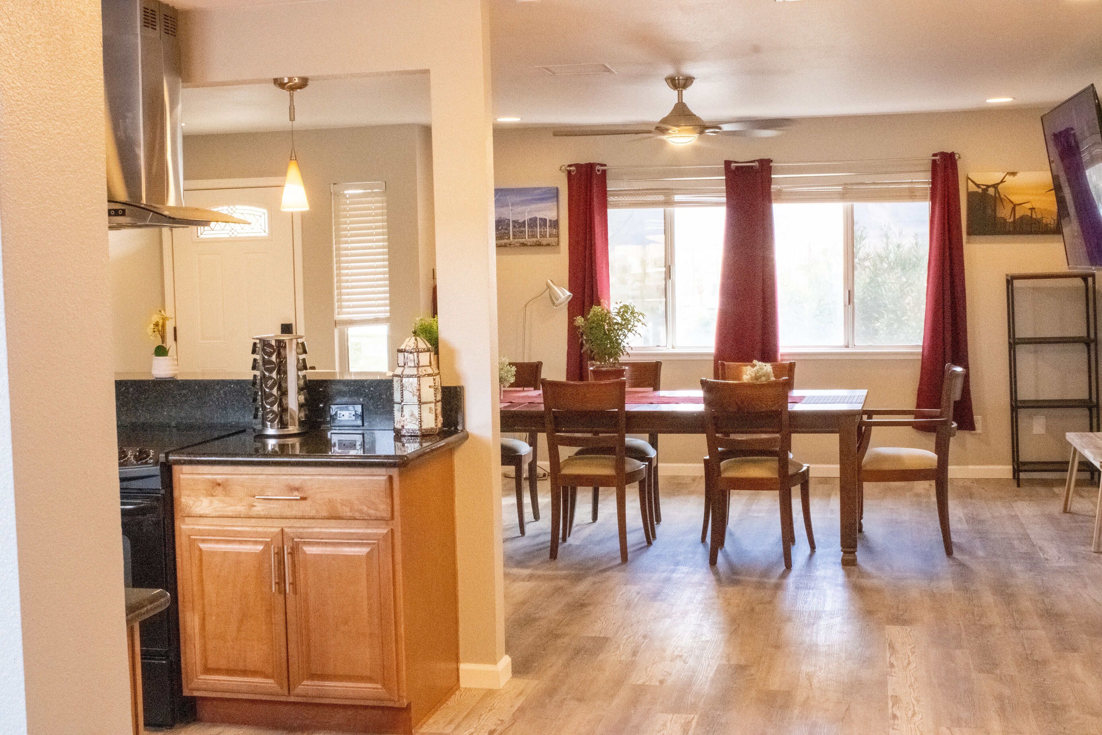 A kitchen with wooden cabinets, a stove, and a dining area with a table and chairs.