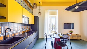A modern kitchen with a black sink, yellow cabinets, and a dining area with a round table and chairs. - Eclectic Apartment 2 in Vasto by Wonderful Italy (Naples)