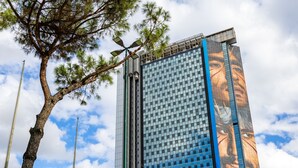 A tall building with a large mural on its side, surrounded by trees and a clear sky. - Eclectic Apartment 2 in Vasto by Wonderful Italy (Naples)