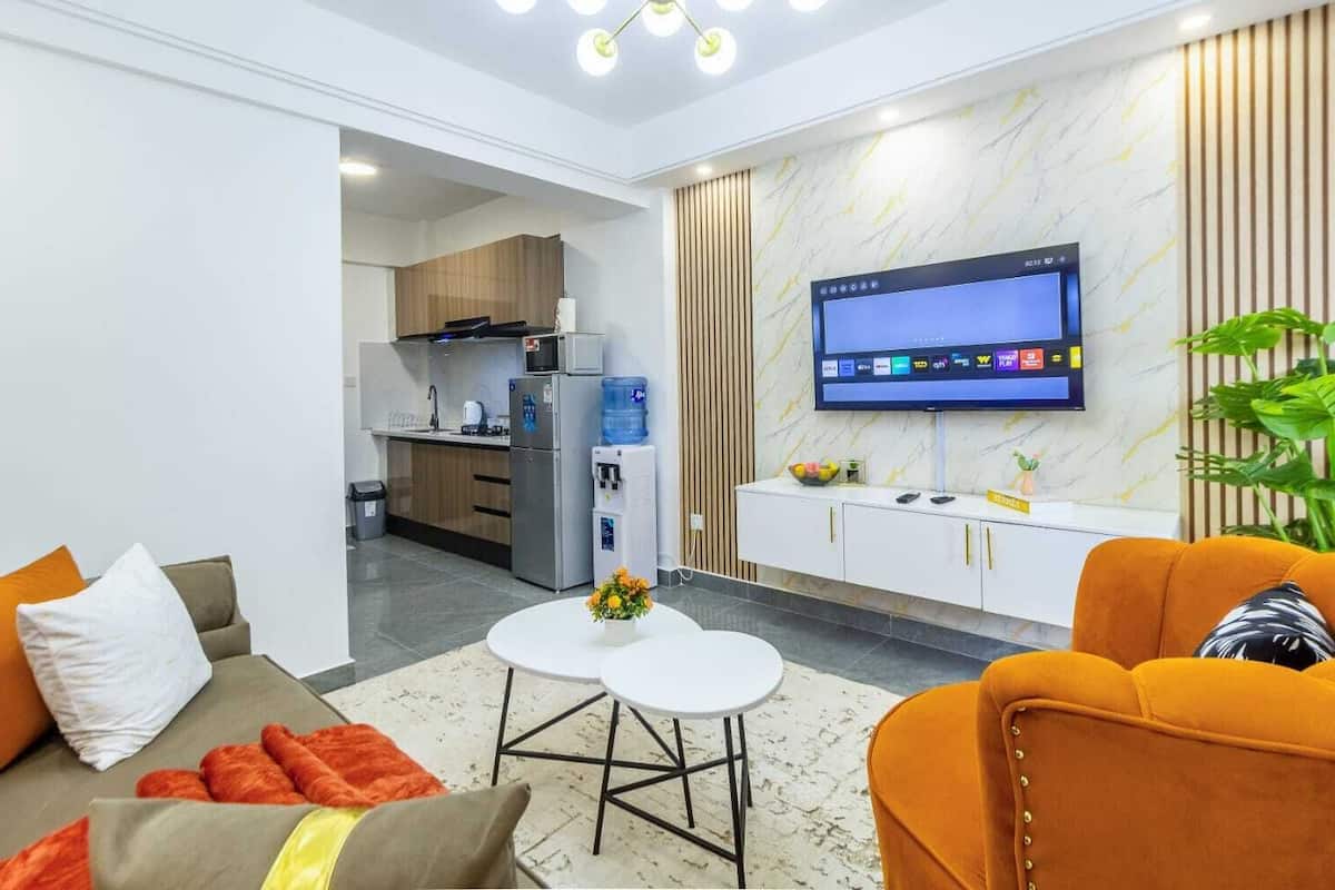 A modern living room with a sofa, a coffee table, and a TV mounted on the wall.