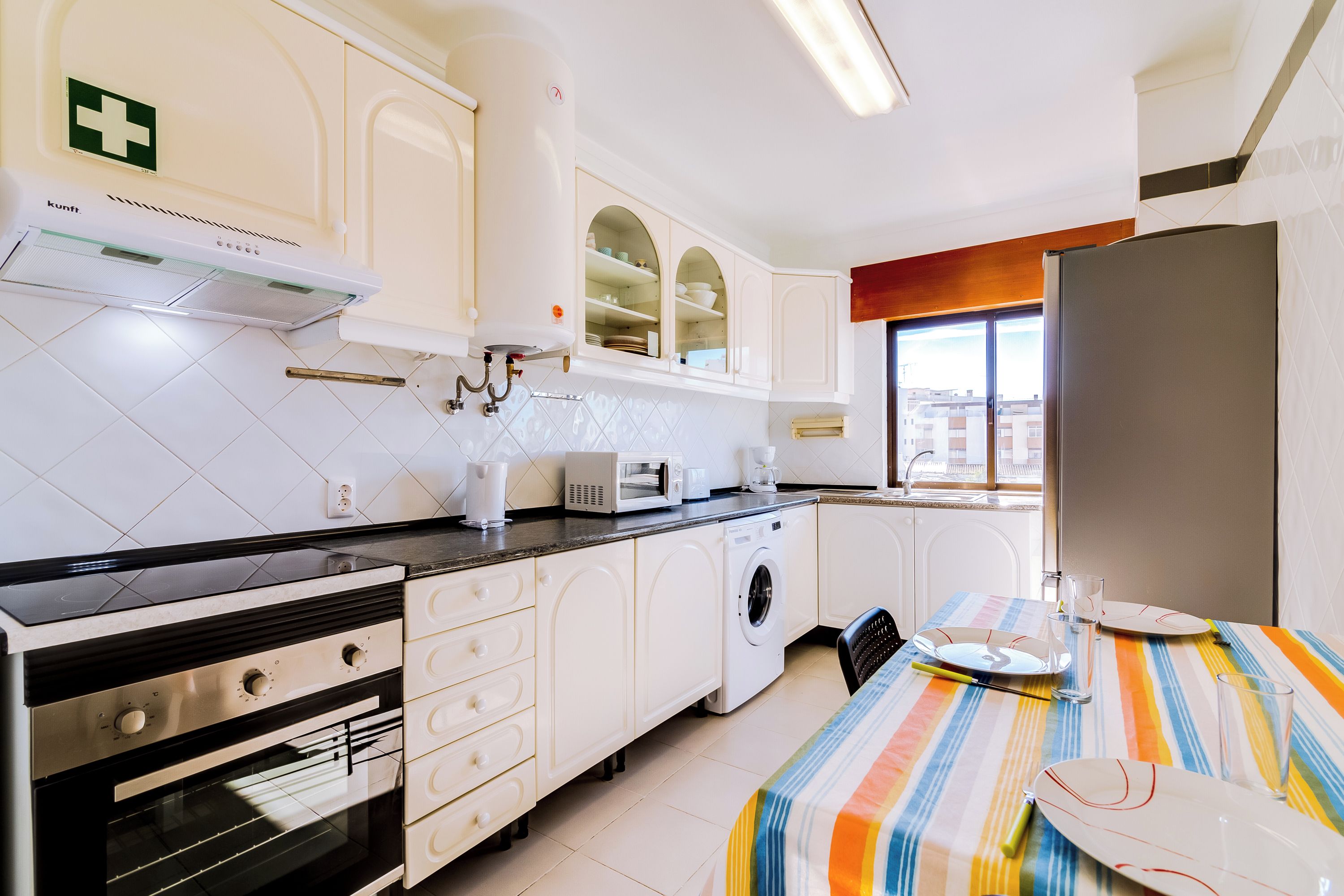 Una cocina moderna con horno empotrado, microondas y lavadora.