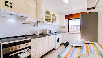 Una cocina moderna con horno empotrado, microondas y lavadora.