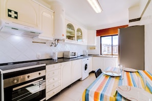 A modern kitchen with a built-in oven, microwave, and washing machine. - Anya (FARO)