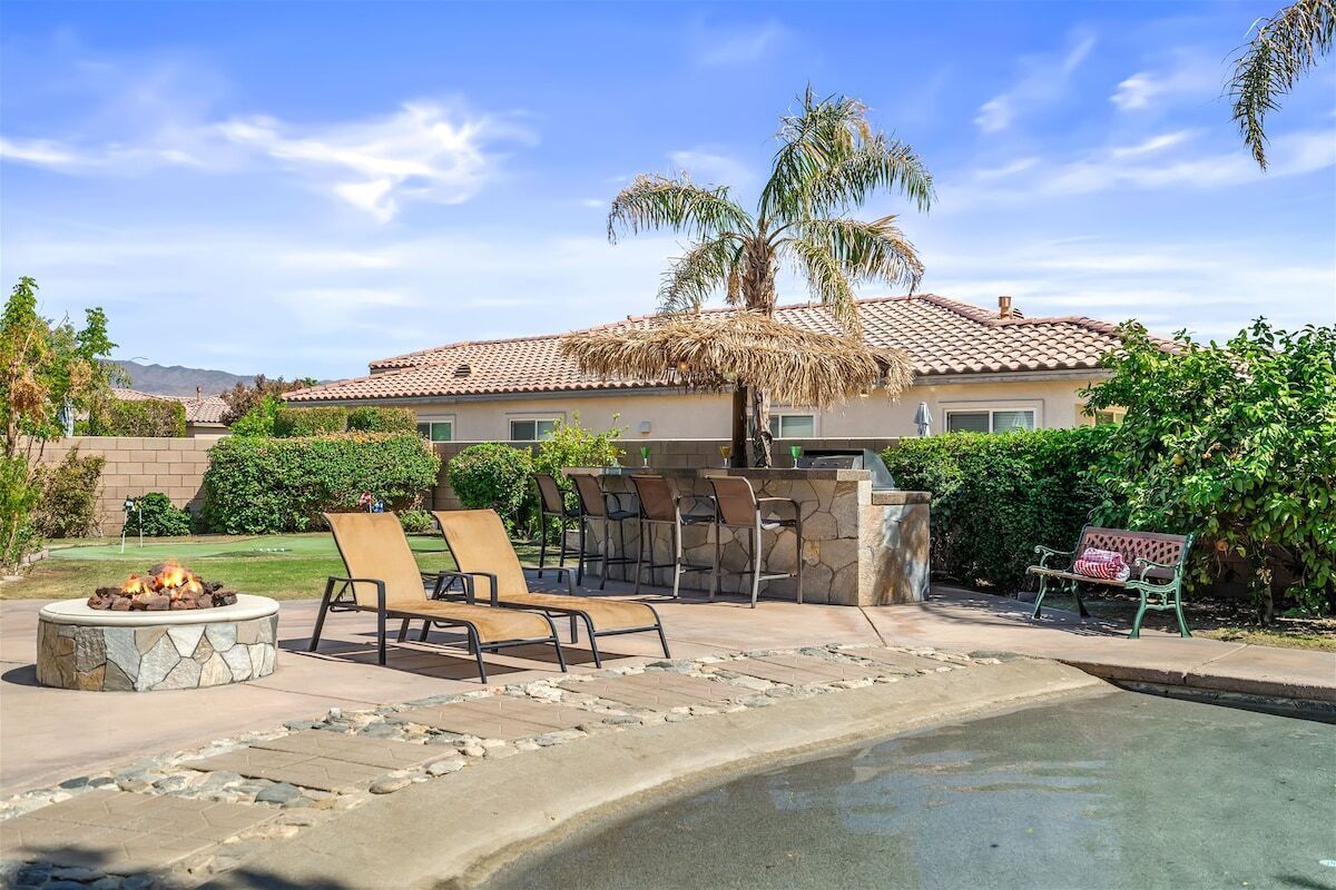 A house with a stone fire pit, outdoor seating, and a swimming pool.