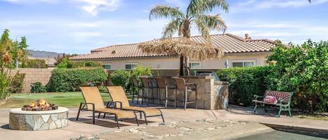 A house with a stone fire pit, outdoor seating, and a swimming pool.