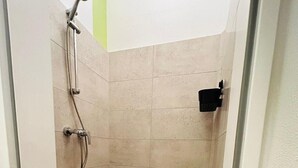 A small, enclosed shower area with tiled walls and a black floor. - House Rasink I Fitters I 160m2 (Ibbenbüren)