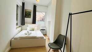A bedroom with a bed, a chair, a radiator, and a window. - House Rasink I Fitters I 160m2 (Ibbenbüren)