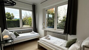 A modern, compact room with two single beds, a small table, and a chair. - House Rasink I Fitters I 160m2 (Ibbenbüren)
