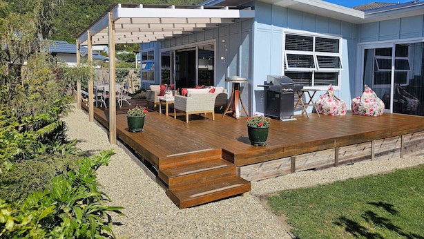 Ein modernes Haus mit einer Holterrasse, Sitzgelegenheiten im Freien und einer Grillanlage.