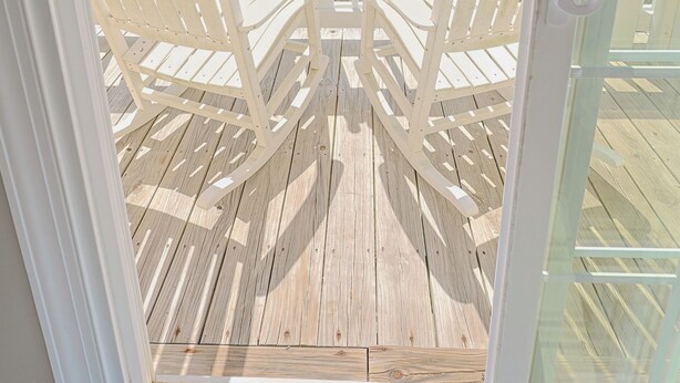 A wooden deck with white chairs facing the ocean. - Ocean Echos – Luxury Oceanfront Vacation Rental in North Topsail Beach (North Topsail Beach)