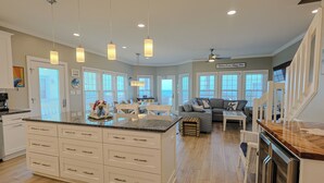 A spacious kitchen with a large island, white cabinetry, and pendant lighting. - Ocean Echos – Luxury Oceanfront Vacation Rental in North Topsail Beach (North Topsail Beach)