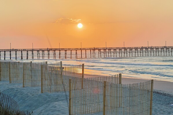 A pier extending into the water with a sunset in the background.