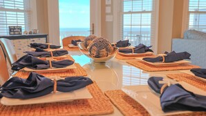 A dining table set with placemats, folded napkins, and a decorative centerpiece. - Ocean Echos – Luxury Oceanfront Vacation Rental in North Topsail Beach (North Topsail Beach)