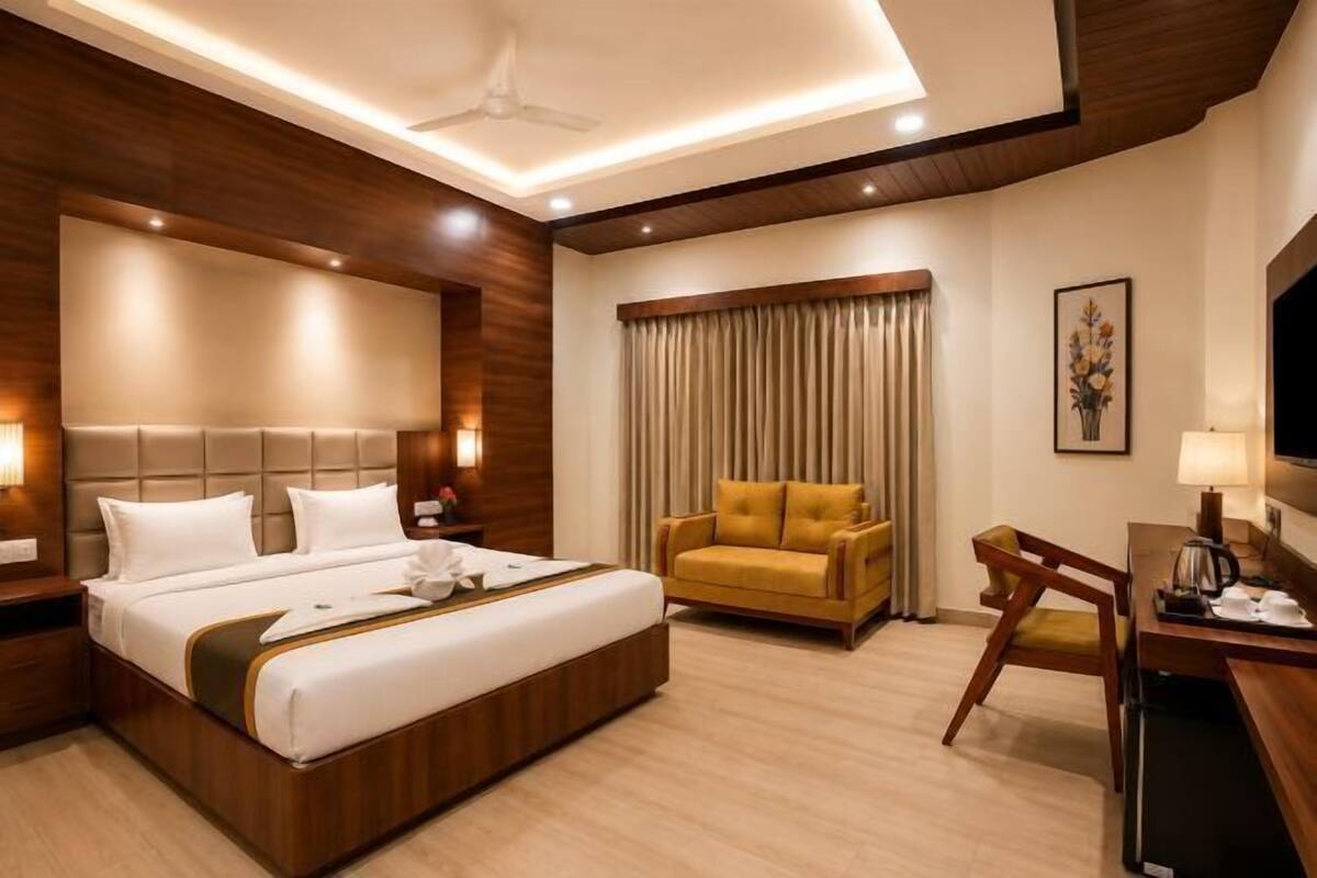 Une chambre d’hôtel avec un grand lit, un canapé, un bureau et un ventilateur de plafond.