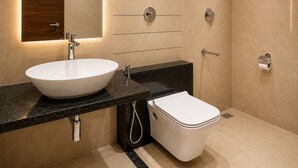 A modern bathroom with a white sink, black countertop, and a toilet. - Hotel Unnati Stay Inn Vijayapura By HRG (Bijapur)