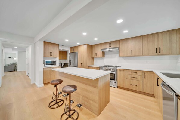 Enjoy cooking in this well-equipped kitchen with a central island, stainless steel appliances, and wooden cabinetry.