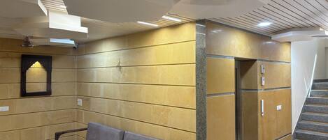 Un vestíbulo con un sofá, una escalera y una pared con un diseño geométrico de azulejos.