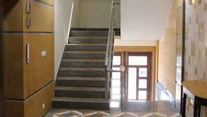Una escalera con un suelo de diseño geométrico, un ventilador de techo y un armario de madera.