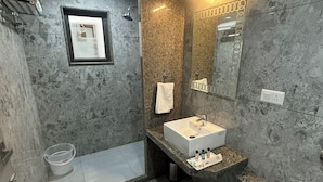 Un baño moderno con lavamanos de encimera de granito, un espejo grande y una zona de ducha.