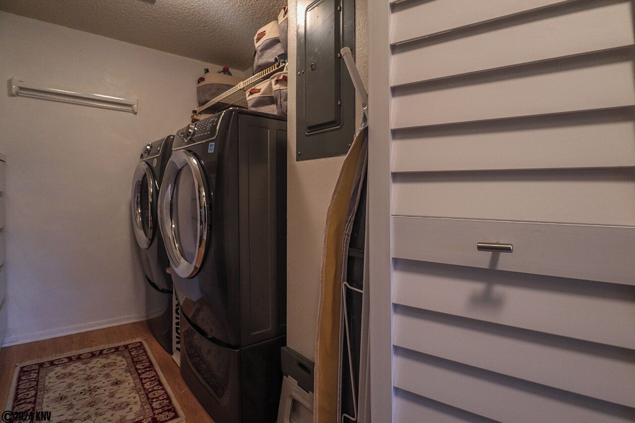 A laundry room with a front-loading washer and dryer, a metal cabinet, and a wooden door.