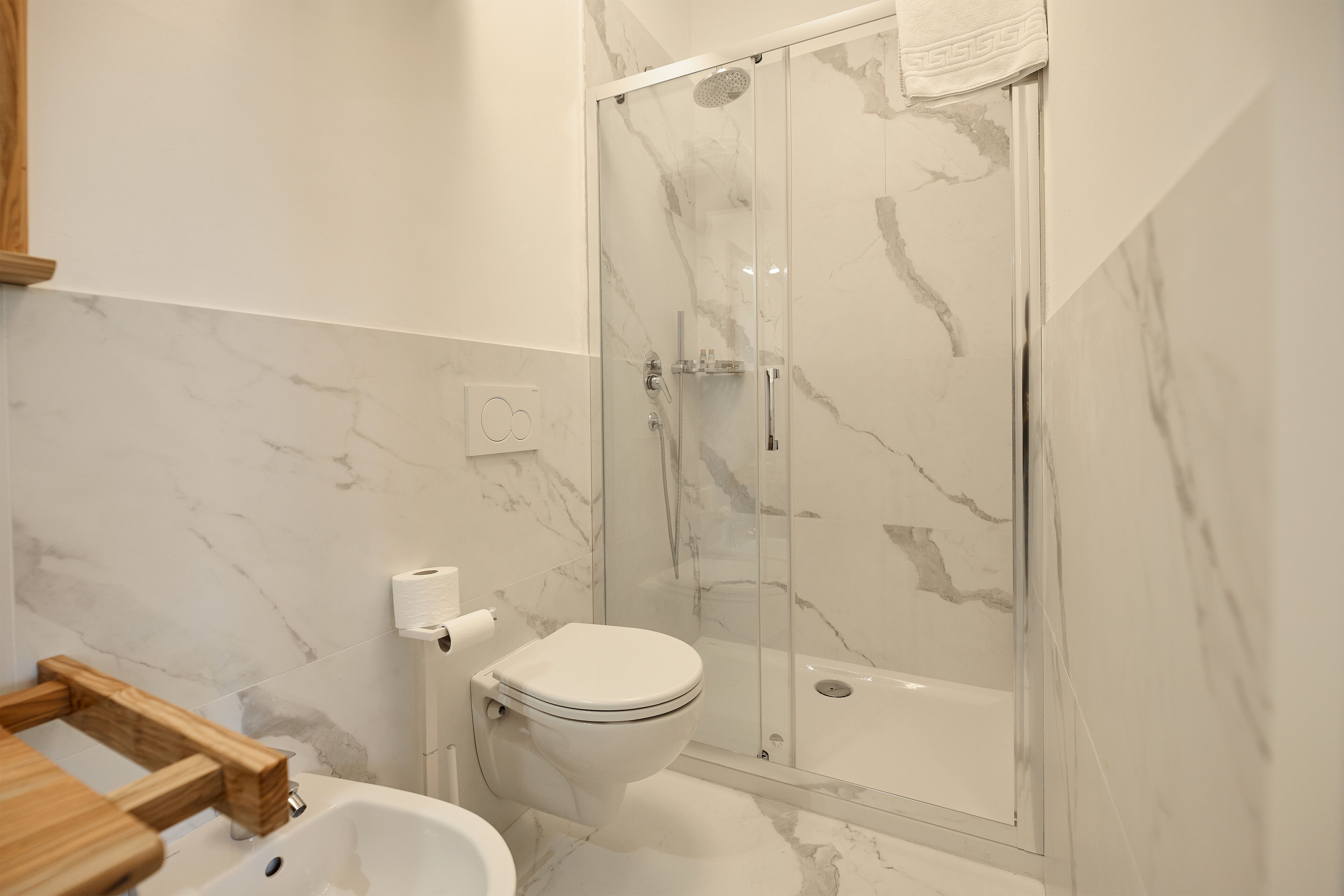 Un baño con inodoro, ducha y paredes de mármol.