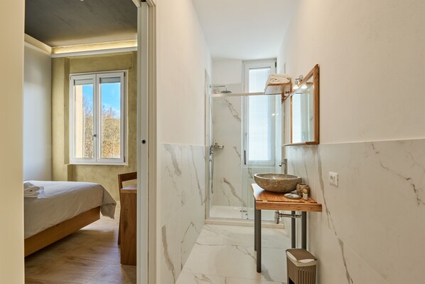 A modern bathroom with a marble floor, a wooden vanity, a large mirror, and a glass shower enclosure. - Hotel Ristorante La Dama nella Vigna (Monteriggioni)