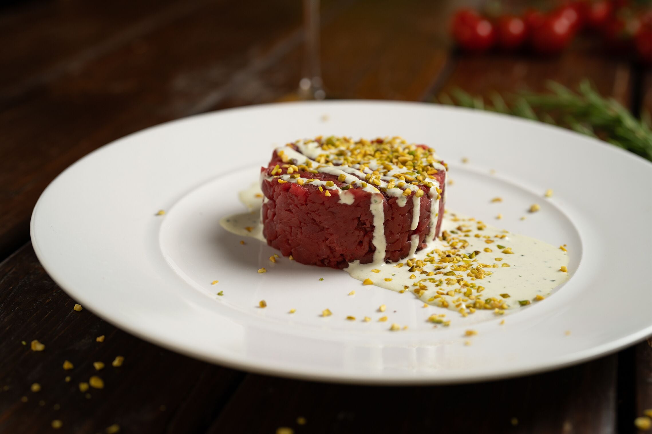 A dessert on a white plate with a drizzle of sauce and sprinkled nuts.