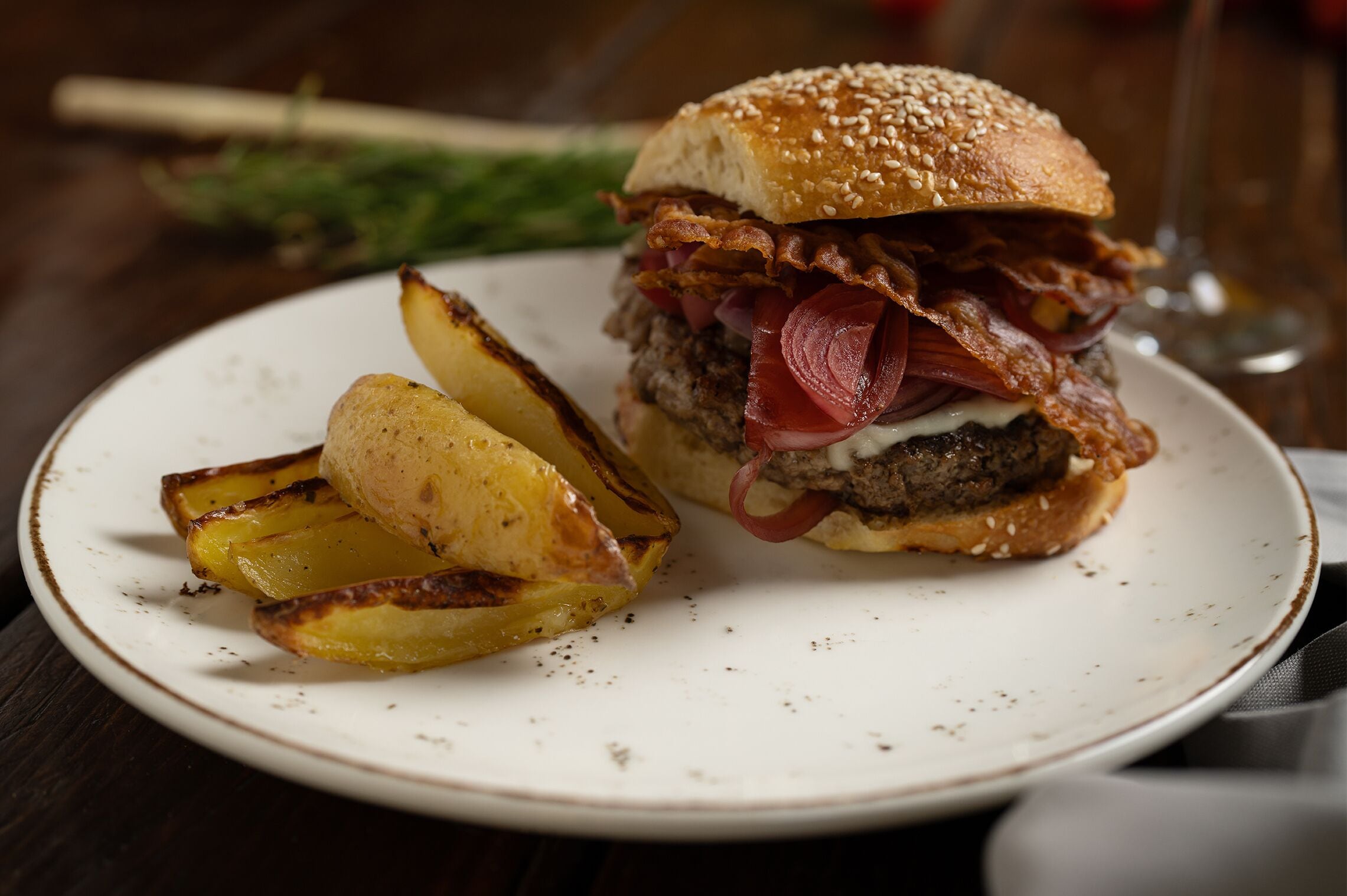 Een bord met een hamburger en geroosterde aardappelen.